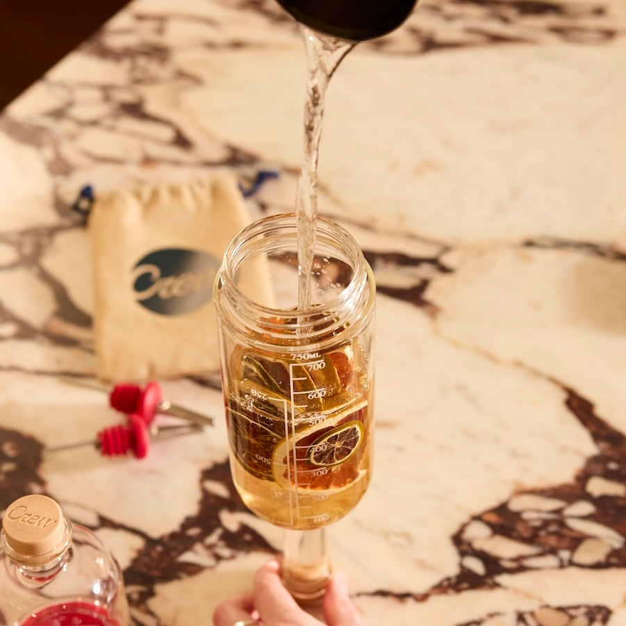 Spirit pouring into cocktail kit infusion mix to make simple cocktails at home