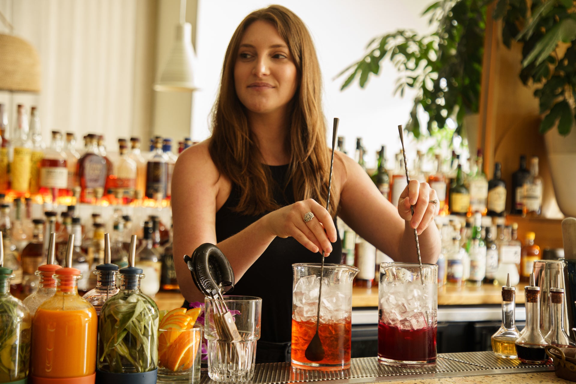 Professional bartender mixing drinks behind a bar using pieces of Crew's cocktail set.